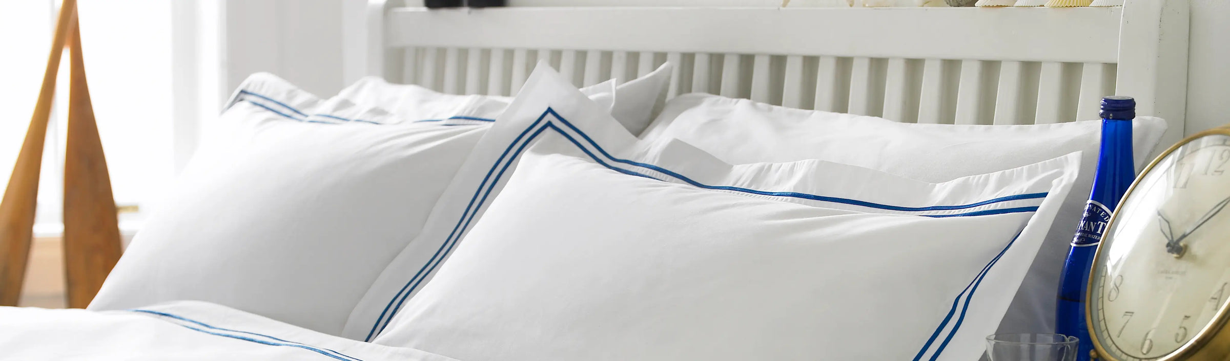 King of cotton White pillows with blue trim on a bed in a bedroom setting.