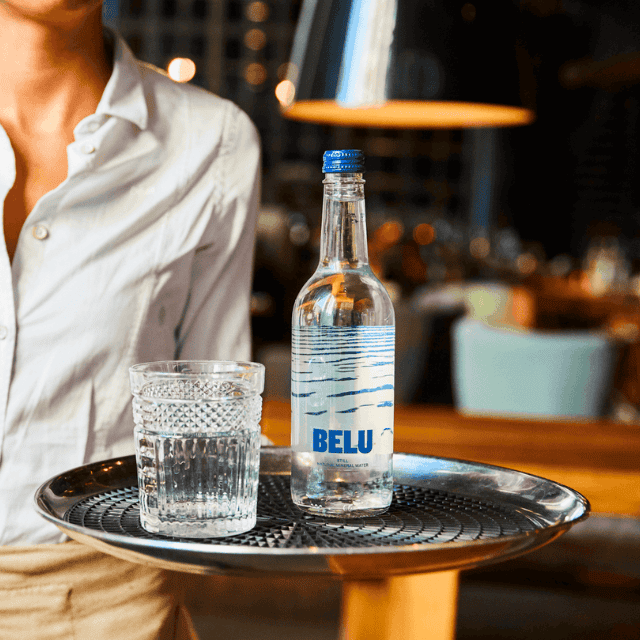 A waitress holding BELU water bottle and glass